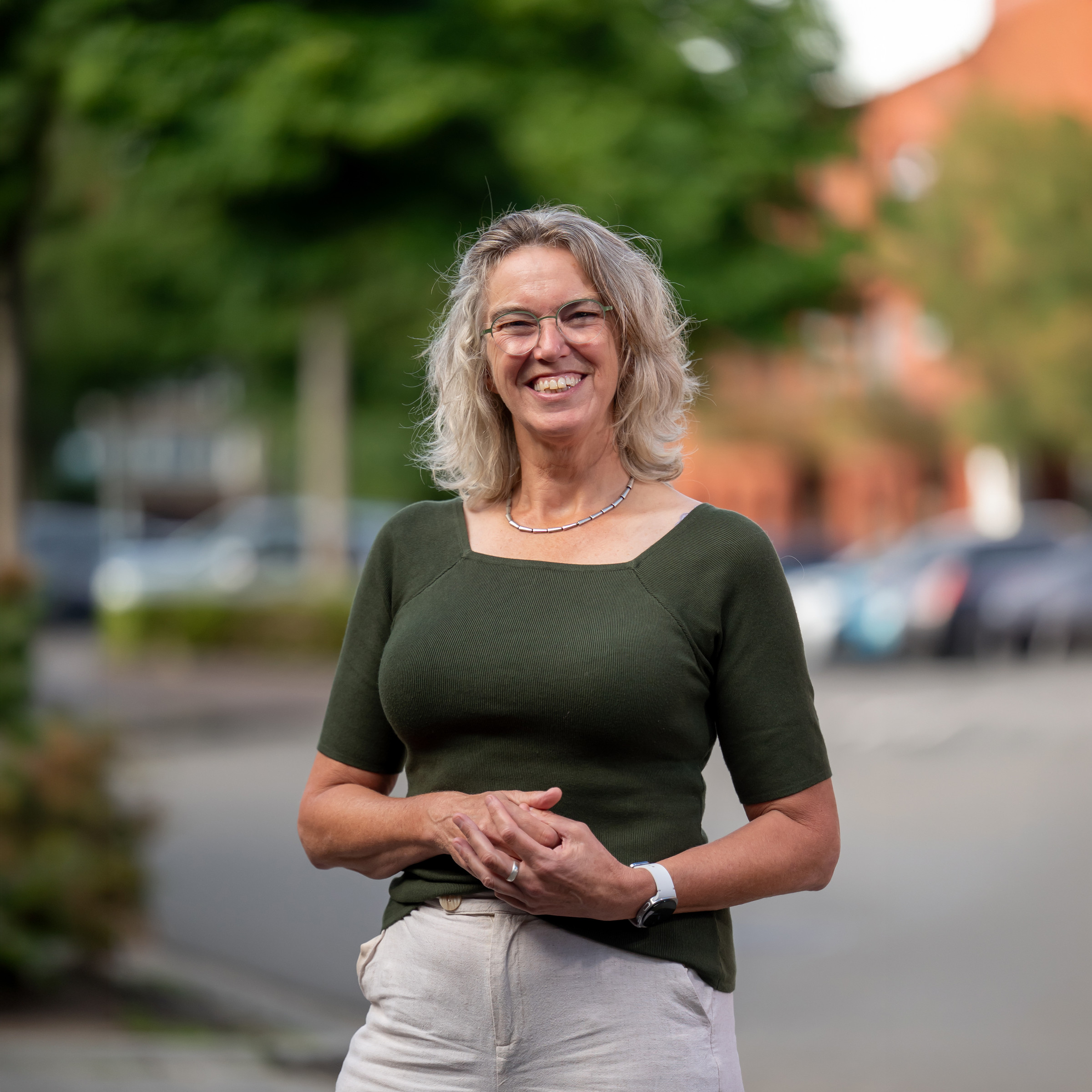 Jeanet Nugteren staat lachend buiten in een donkergroene top.